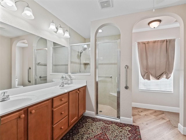 bathroom with toilet, hardwood / wood-style floors, vanity, and a shower with shower door