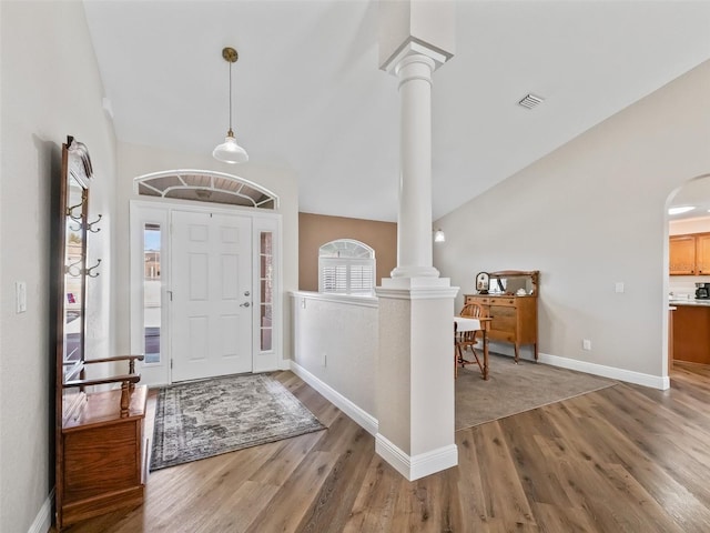 foyer featuring vaulted ceiling, decorative columns, and wood-type flooring