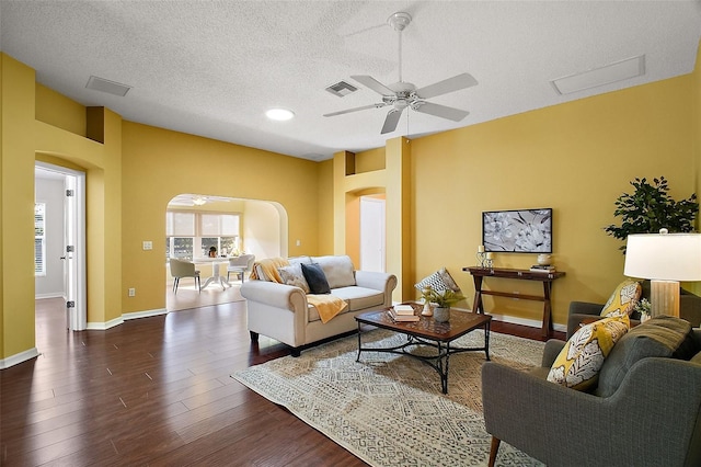 living room with ceiling fan, dark hardwood / wood-style floors, and a textured ceiling