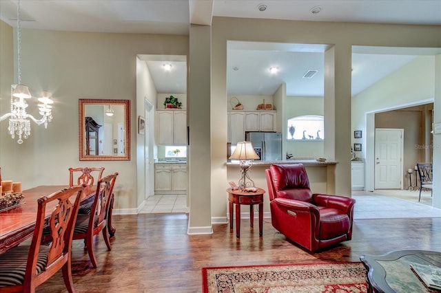 living room featuring vaulted ceiling, light hardwood / wood-style floors, and a notable chandelier