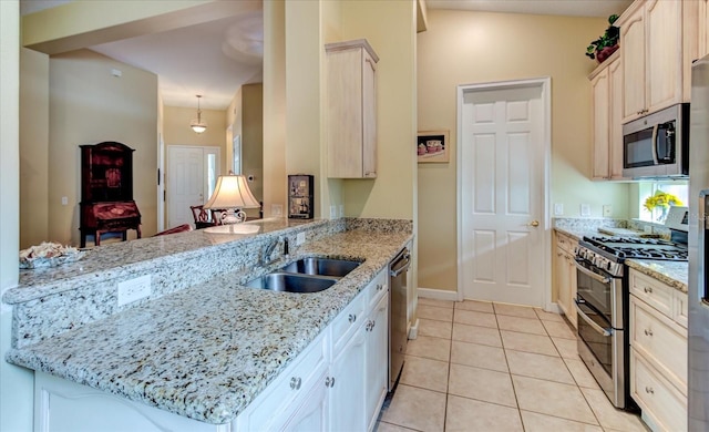 kitchen featuring light tile patterned flooring, sink, kitchen peninsula, stainless steel appliances, and light stone countertops