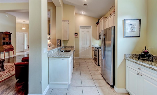 kitchen with appliances with stainless steel finishes, sink, hanging light fixtures, light tile patterned floors, and light stone countertops