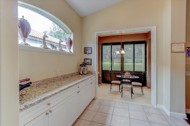 kitchen featuring white cabinetry, pendant lighting, light stone counters, and light tile patterned flooring