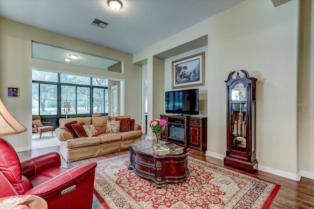 living room with dark hardwood / wood-style flooring and a textured ceiling