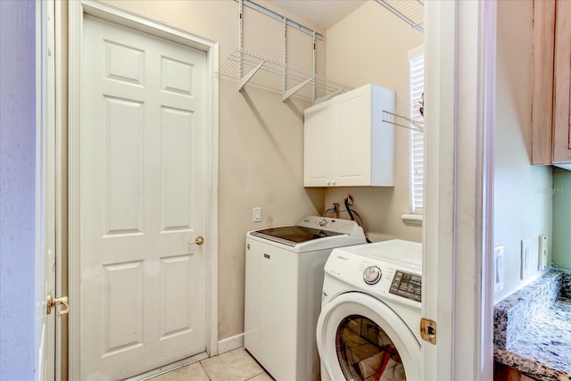 laundry room with cabinets, washing machine and dryer, and light tile patterned floors