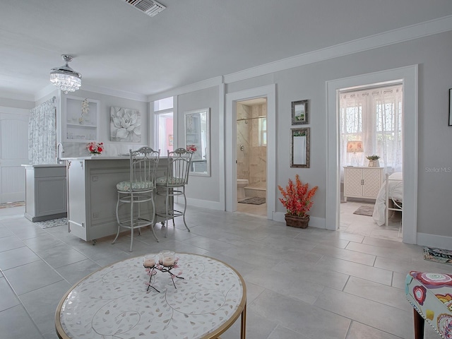 kitchen featuring ornamental molding, a kitchen breakfast bar, gray cabinets, and light tile patterned floors