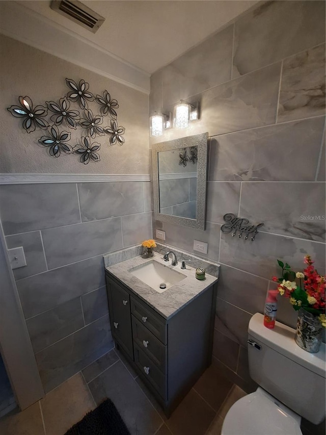 bathroom featuring vanity, tile walls, and toilet