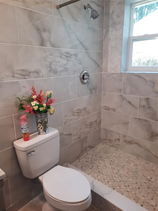 bathroom with tiled shower, toilet, and tile walls