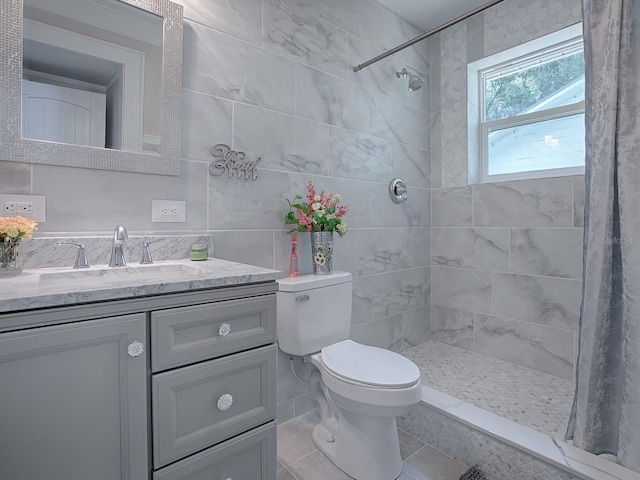 bathroom with tile walls, vanity, toilet, and tiled shower