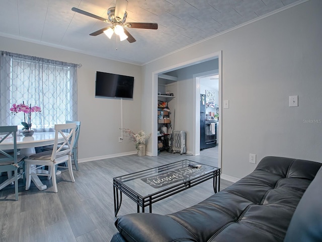 living room with hardwood / wood-style flooring, ceiling fan, and ornamental molding