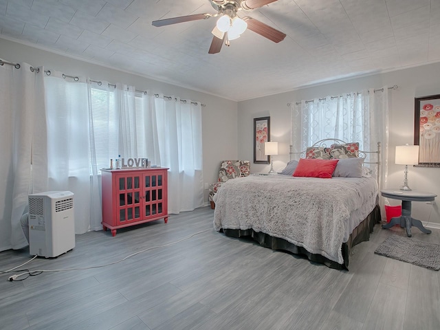 bedroom with ornamental molding, hardwood / wood-style floors, and ceiling fan