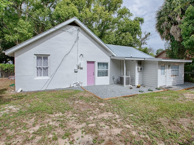 back of property with cooling unit, central AC unit, and a lawn