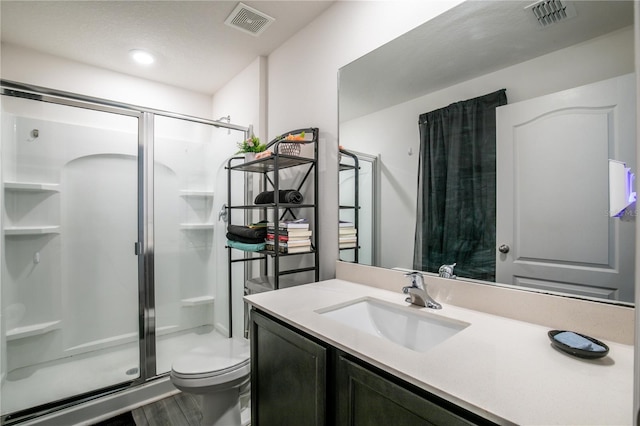 bathroom featuring vanity, hardwood / wood-style flooring, a shower with shower door, and toilet