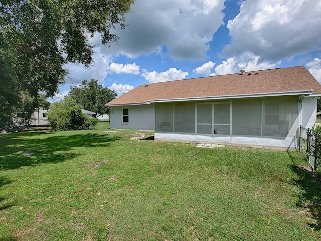 rear view of house featuring a lawn and a sunroom