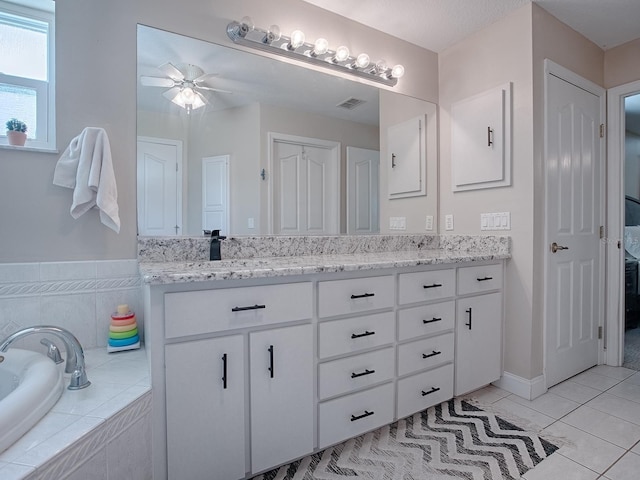 bathroom with ceiling fan, tile patterned floors, vanity, and tiled bath