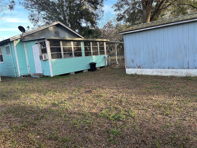 exterior space featuring cooling unit, a sunroom, and a lawn