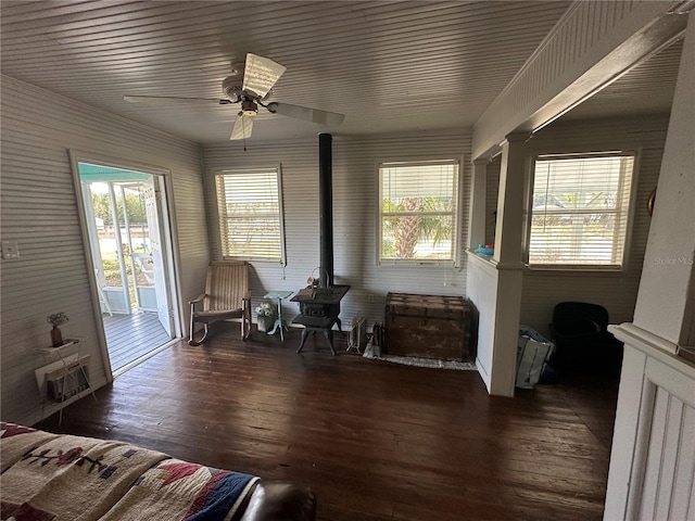 interior space with ceiling fan, a wood stove, dark hardwood / wood-style floors, and a healthy amount of sunlight