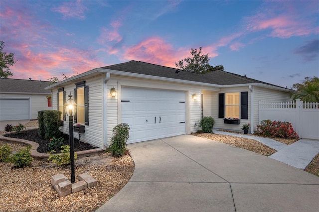 ranch-style home featuring a garage, concrete driveway, and fence