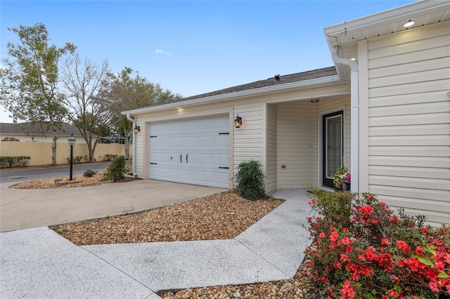 exterior space with concrete driveway, an attached garage, and fence