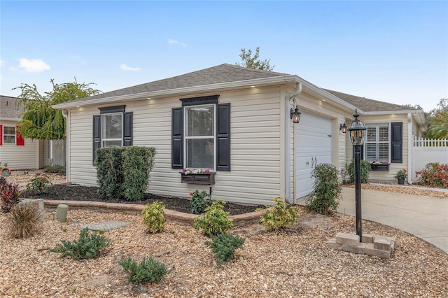 view of side of property with an attached garage, driveway, and roof with shingles