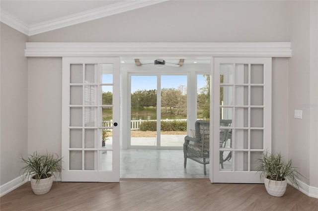 doorway to outside with crown molding, baseboards, vaulted ceiling, and wood finished floors