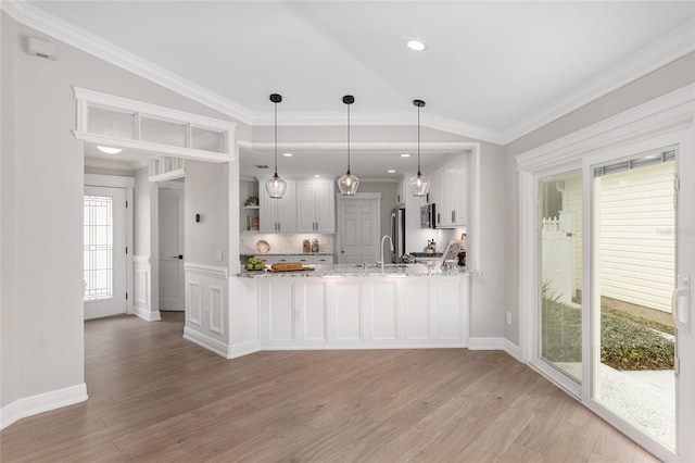 kitchen with light stone counters, white cabinets, and ornamental molding