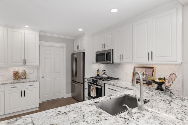 kitchen with stainless steel appliances, white cabinetry, and a sink