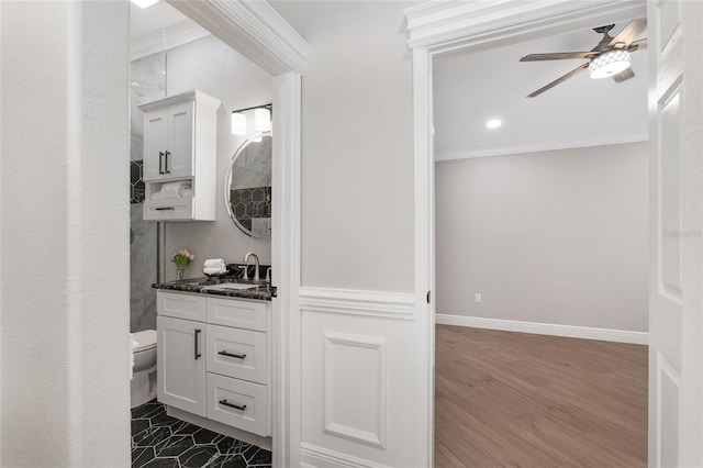 full bath with baseboards, a ceiling fan, toilet, crown molding, and vanity