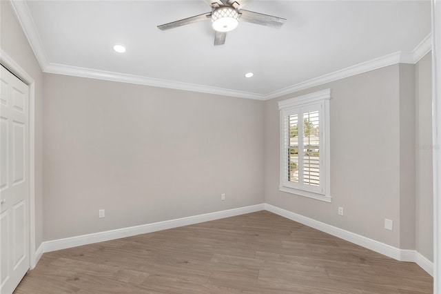 spare room featuring a ceiling fan, light wood-style flooring, baseboards, and crown molding