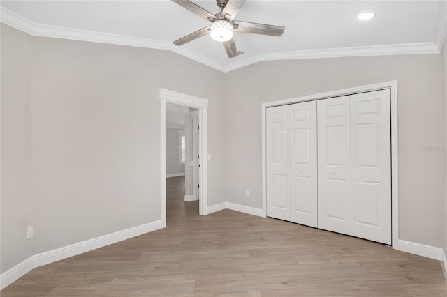 unfurnished bedroom with light wood-style floors, vaulted ceiling, crown molding, and baseboards