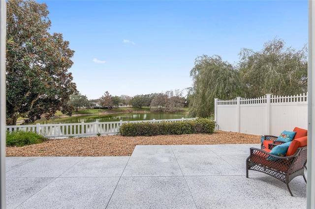 view of patio featuring a water view and fence