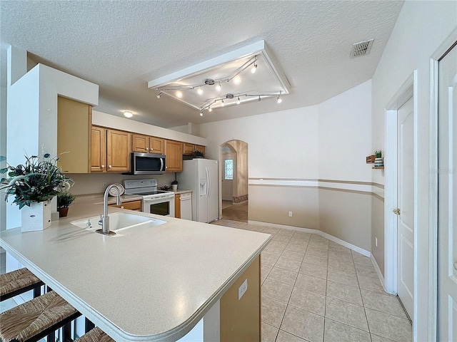 kitchen featuring sink, a breakfast bar area, white appliances, and kitchen peninsula