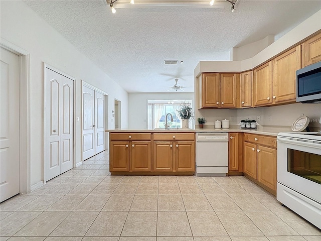 kitchen featuring sink, white appliances, light tile patterned floors, and kitchen peninsula