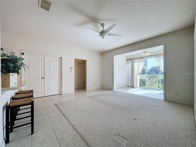 unfurnished living room featuring ceiling fan, light tile patterned floors, and a textured ceiling