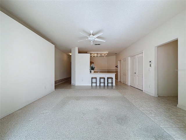 unfurnished living room with ceiling fan, sink, and a textured ceiling