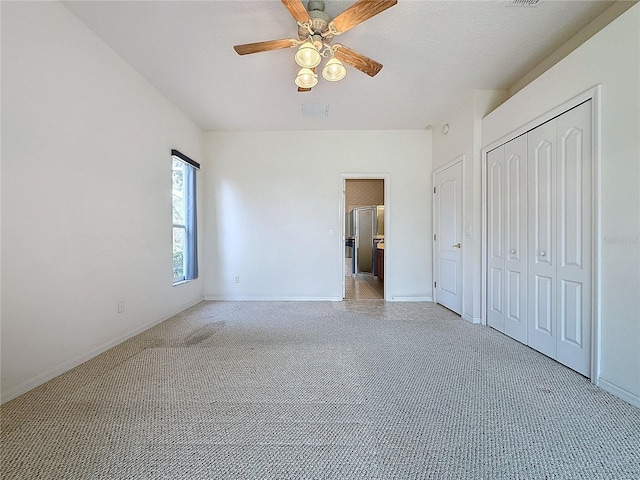 unfurnished bedroom featuring light carpet, ceiling fan, and a closet