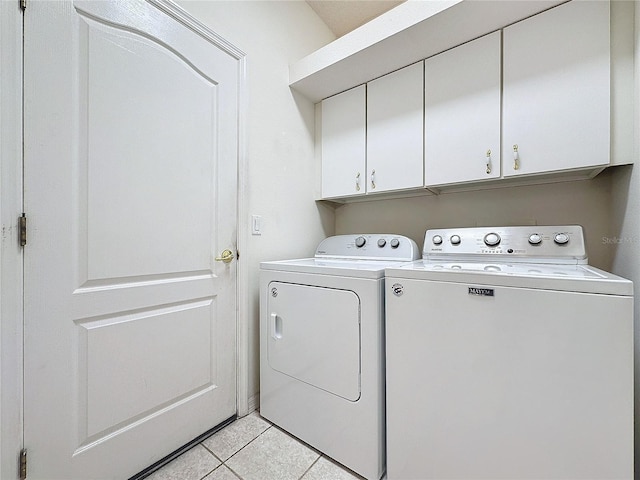 washroom featuring cabinets, washing machine and dryer, and light tile patterned floors