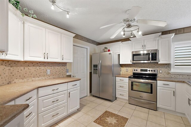 kitchen with white cabinetry, light tile patterned floors, ceiling fan, stainless steel appliances, and a textured ceiling
