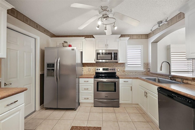 kitchen featuring sink, light tile patterned floors, white cabinets, and appliances with stainless steel finishes
