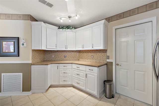 kitchen with white cabinetry, light tile patterned floors, and backsplash