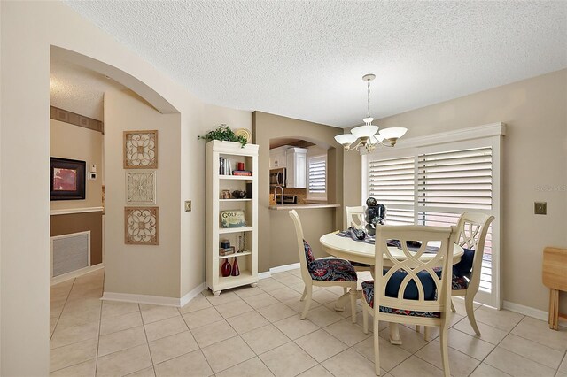 tiled dining area with a textured ceiling and an inviting chandelier