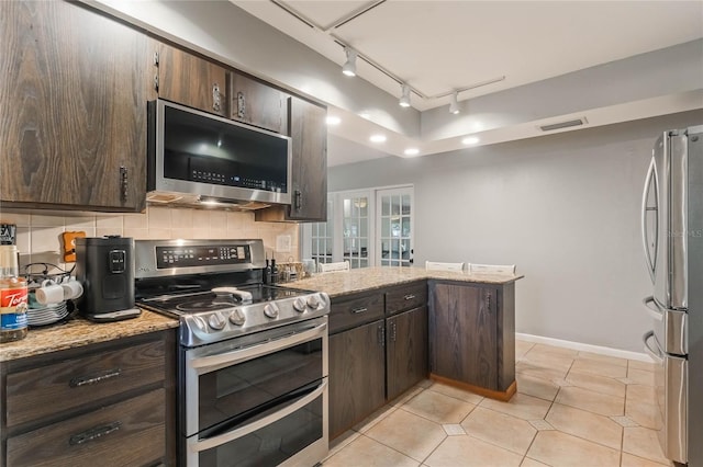 kitchen with backsplash, light stone counters, kitchen peninsula, stainless steel appliances, and dark brown cabinets