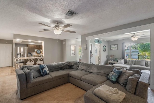 living room featuring ceiling fan, light colored carpet, and a textured ceiling