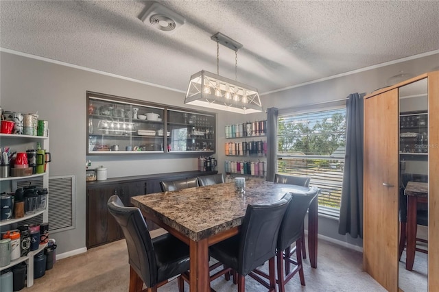 carpeted dining area with a textured ceiling, ornamental molding, and a healthy amount of sunlight