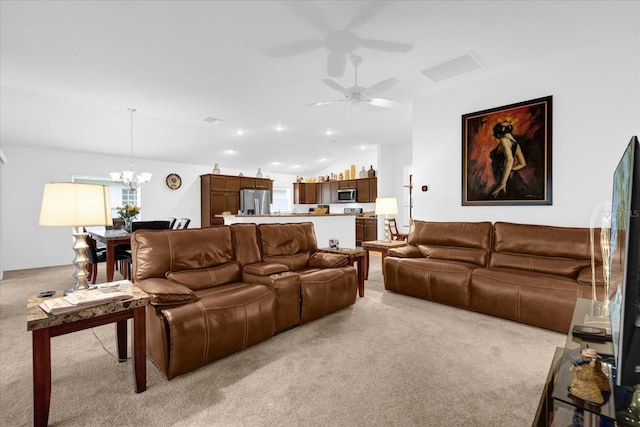 carpeted living room featuring ceiling fan with notable chandelier and vaulted ceiling