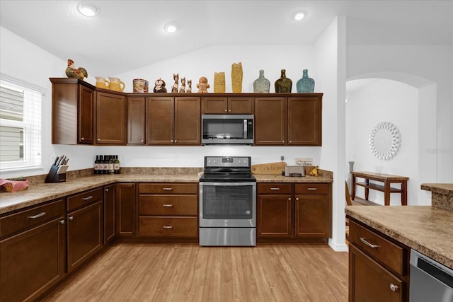 kitchen with dark brown cabinetry, light wood-type flooring, vaulted ceiling, and appliances with stainless steel finishes