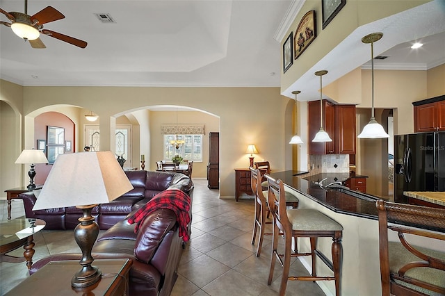 tiled living room featuring ornamental molding and ceiling fan