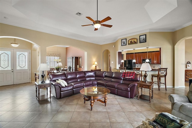 living room featuring crown molding, light tile patterned floors, and a tray ceiling