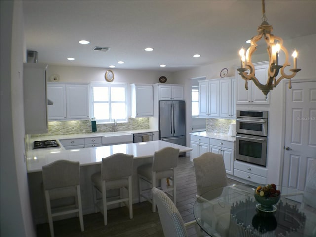 kitchen featuring stainless steel appliances, hanging light fixtures, a healthy amount of sunlight, and white cabinets