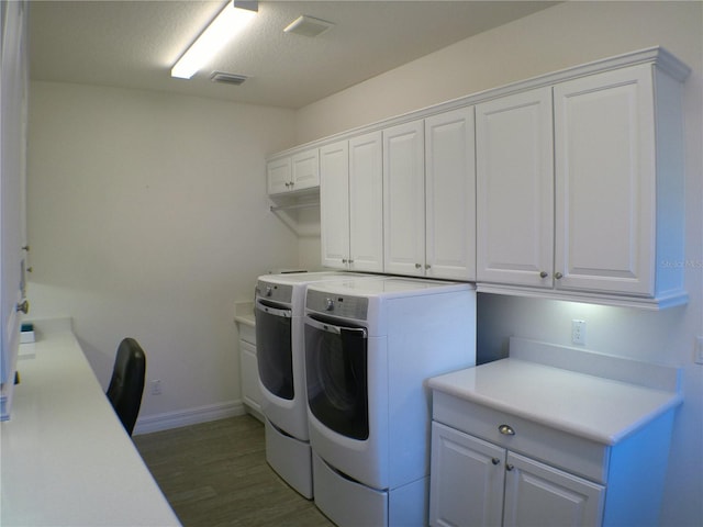 washroom with cabinets, washing machine and clothes dryer, and dark hardwood / wood-style flooring